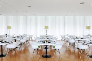 uma sala de jantar com mesas brancas e cadeiras brancas em Open Village Sports Hotel & Spa Club em Guimarães