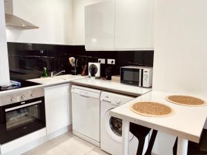 a white kitchen with a sink and a dishwasher at "Garenne 1" Cosy 2 pièces quartier haut climatisé avec balcon ! in Sète +5 photos