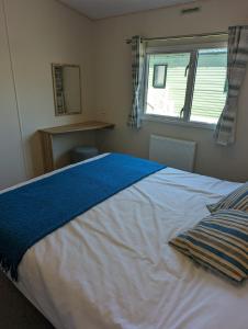ein Schlafzimmer mit einem großen weißen Bett und einem Fenster in der Unterkunft LOVELY BRIGHT MODERN CARAVAN SWANAGE on PEACEFUL AND TRANQUIL HOLIDAY PARK in Swanage