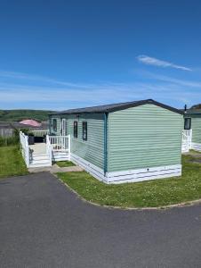 ein grün-weißes Gebäude am Straßenrand in der Unterkunft LOVELY BRIGHT MODERN CARAVAN SWANAGE on PEACEFUL AND TRANQUIL HOLIDAY PARK in Swanage