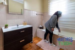 a person standing in a bathroom next to a sink at Casa da Avó Natal in Lajes