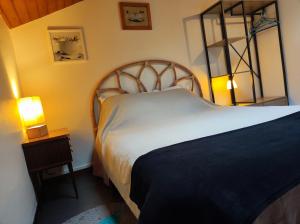 a bedroom with a large bed and a night stand with a lamp at LE COURANT D'HUCHET in Moliets-et-Maa