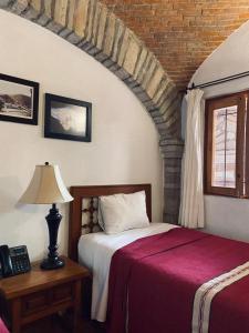 a bedroom with a bed and a lamp and a window at Hotel Socavon in Guanajuato