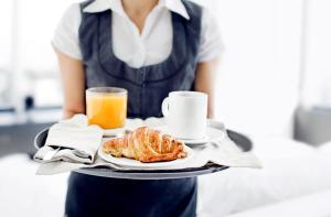 a waitress holding a tray with a plate of food and orange juice at Luxury Suite Koksijde 310 - Adults only in Koksijde +8 photos