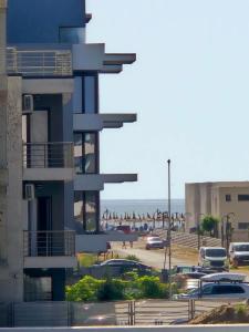 a building with cars parked in a parking lot next to a beach at Seb apartment mamaia nord in Năvodari