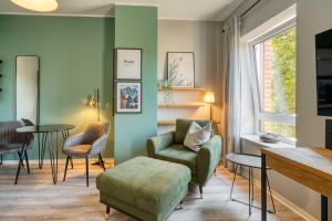 a living room with a green chair and a table at One Moment Boardinghouse - Porta Westfalica in Porta Westfalica
