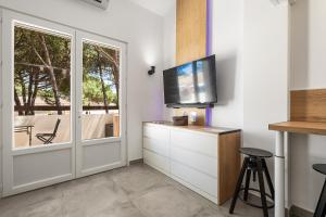 een woonkamer met een tv en een glazen schuifdeur bij Cap d'Agde Suit'Appart T2 Pinede 31 M2 in Cap d'Agde