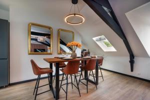 a dining room with a table with chairs and mirrors at Dans les Airs in Quimper