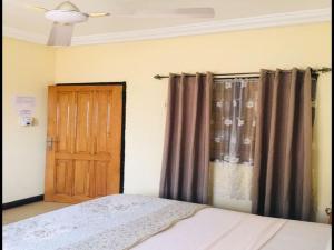 a bedroom with a bed and a wooden door at Single Room - 1st Floor in Accra +12 photos
