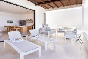 a living room with white chairs and a kitchen at Stunning Beachfront Residence with Resort Perks in El Pescadero