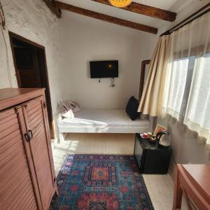 a room with a bed and a tv on the wall at Kapela Taş Otel Alaçatı in Çeşme