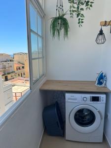 Un lavadero con lavadora y ventana. en Casa Janivo, en Armação de Pêra