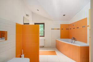 ein orange-weißes Badezimmer mit Badewanne und Toilette in der Unterkunft Chill&SPA Villa 30 min od Warszawy, Jacuzzi, Sauna, Sport in Konstancin-Jeziorna + 25 Fotos