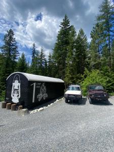 two cars parked next to a trailer and a truck at The Camp Haus A Montana Tiny Cabin Forest Retreat in Lakeside