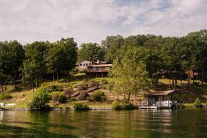 a house on a hill next to a body of water at Lake Escape To An Elegant 4 Br Home in Huddleston