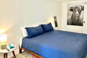 a bedroom with a blue bed with a cow picture on the wall at Narrow Gauge Nook in Durango