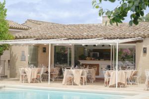 a patio with tables and chairs next to a pool at Hôtel La Figuière in Saint-Tropez