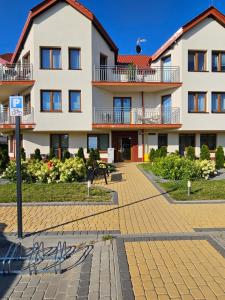 un grand bâtiment blanc avec un toit rouge dans l'établissement Apartament Morskie zacisze Darłówko, à Darłówko