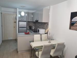 une cuisine avec une table et des chaises et une cuisine avec des armoires blanches dans l'établissement Apartamento Torres del Sol, à Arona