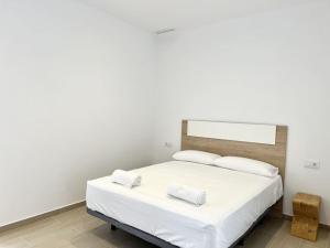 een slaapkamer met een bed met witte lakens en kussens bij Moderno apartamento con terraza en la azotea in Roses