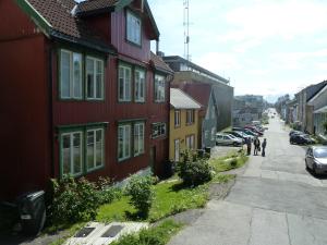 a group of people walking down a street next to houses at Red Old House Tromsø Apartment in Tromsø +7 photos