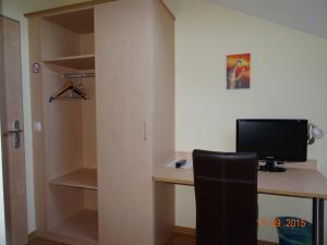 a room with a desk with a computer and a closet at Pension Alram Hof in Eggenfelden