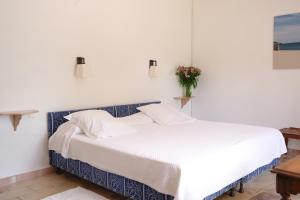 a white bed in a bedroom with a vase of flowers at Hôtel La Figuière in Saint-Tropez