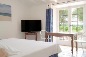 a bedroom with a bed and a tv and a window at Hôtel La Figuière in Saint-Tropez