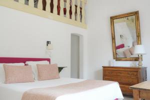 a bedroom with a bed with a mirror and a dresser at Hôtel La Figuière in Saint-Tropez