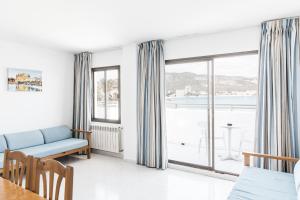 a living room with a couch and a large window at Apartamentos Balear Beach in Palmanova +9 photos