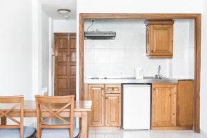 a kitchen with wooden cabinets and a sink and a table at Apartamentos Balear Beach in Palmanova