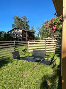two chairs and a table in front of a fence at Saulkrasti Beach Cottage in Saulkrasti