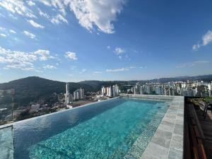 a swimming pool with a view of a city at Loft de Luxo "Novo" no Coração de Blumenau a 10min a Pé da Vila Germânica in Blumenau