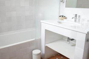 a white bathroom with a sink and a tub at Hôtel La Figuière in Saint-Tropez