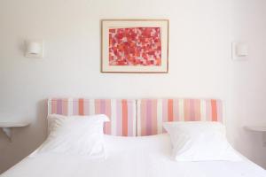 a bedroom with a white bed with a painting on the wall at Hôtel La Figuière in Saint-Tropez