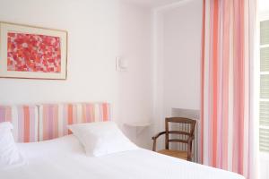 a bedroom with a bed and a chair next to a window at Hôtel La Figuière in Saint-Tropez