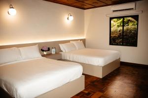two beds in a hotel room with a window at Hotel Boutique Rebequet in Boquete