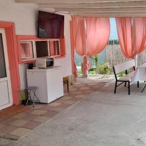 una cucina con tende rosa, tavolo e sedie di Casa G&A Geta și Alexandru a Sulina