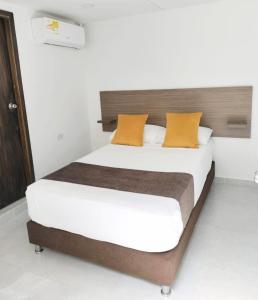 una camera da letto con un grande letto con cuscini arancioni di Ayenda Hotel Helenas a Ríohacha