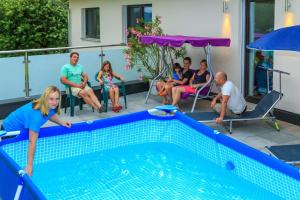 a group of people sitting around a swimming pool at Wittinghof in Julbach