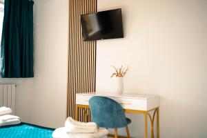 a desk with a blue chair and a tv on a wall at Dimora Prometeo in Bari