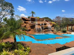 a pool with a waterfall in a resort at Pousada do Batata in Capitólio