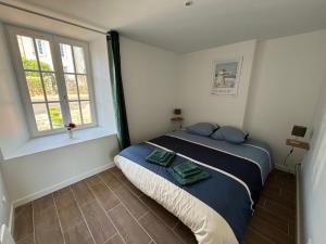 a bedroom with a bed with blue pillows and a window at Gites du Manoir de Kergoniou Saint Joseph in Paimpol