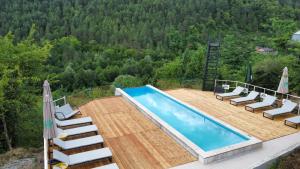 a swimming pool with chairs and a deck with a mountain at Glamping Georgia Krikhi in Ambrolauri