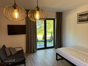 een slaapkamer met twee kroonluchters en een bed en een stoel bij Apartamenty La Venda in Darlowko
