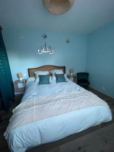 a bedroom with a large bed with blue walls at Le nid des hirondelles in Cucq
