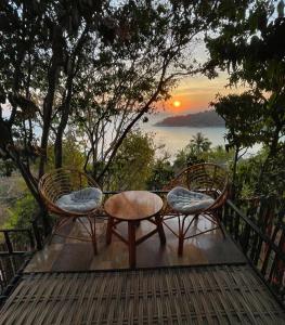 dos sillas y una mesa con una puesta de sol en el fondo en LOOK Bungalows, en Ko Tao