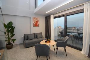 ein Wohnzimmer mit Sofa und einem Tisch mit Stühlen in der Unterkunft Mavili Luxury Apartments in Kavala
