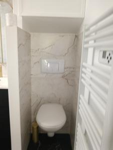 a small bathroom with a white toilet and marble walls at Escale Côte d'Amour in Pornichet