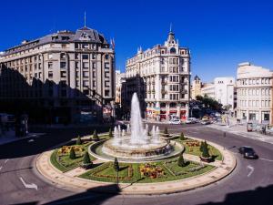 a fountain in the middle of a city with buildings at Zentric Hostel in León